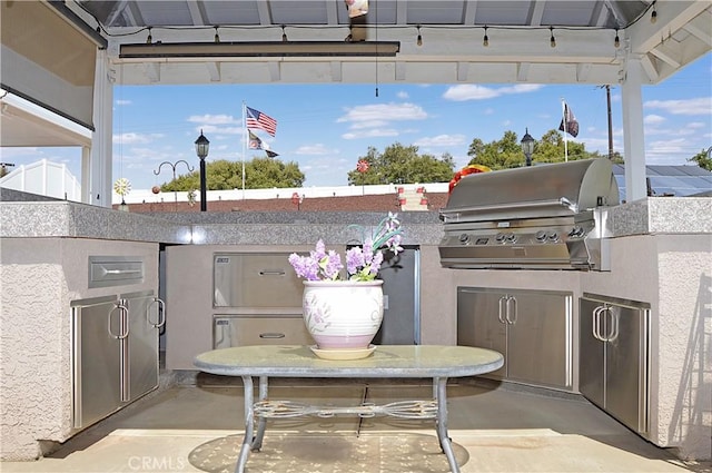 view of patio with exterior kitchen and a grill