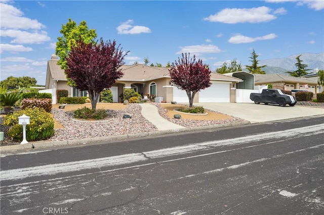 obstructed view of property with a mountain view, stucco siding, an attached garage, and driveway