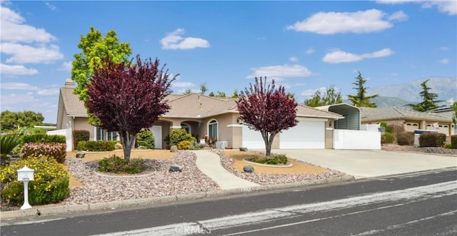 38256 Wild Poppy Ln, Yucaipa, CA 92399 - view of front of home with concrete driveway, a mountain view, an attached garage, stucco siding, and fence