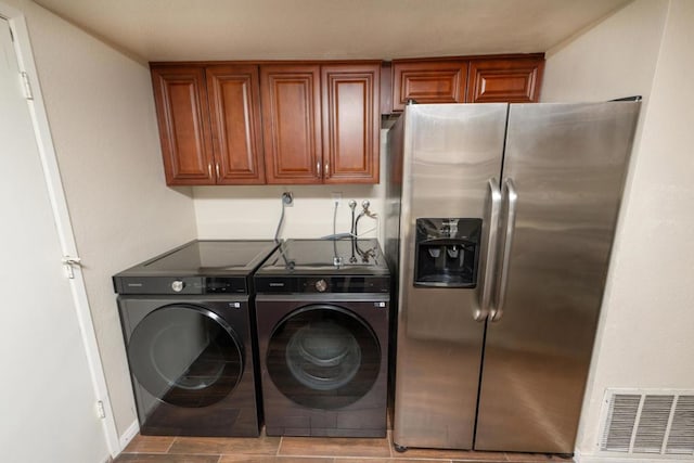 clothes washing area with laundry area, visible vents, washing machine and dryer, and baseboards