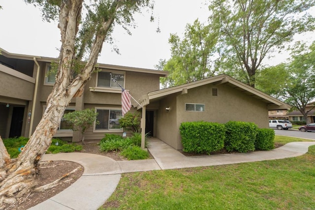 view of front of home featuring stucco siding and a front yard