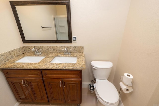 full bathroom featuring double vanity, a sink, baseboards, and toilet