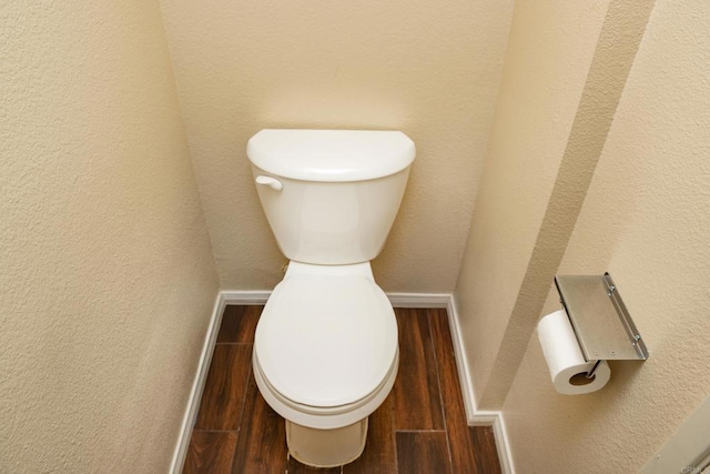 bathroom featuring baseboards, a textured wall, toilet, and wood finished floors
