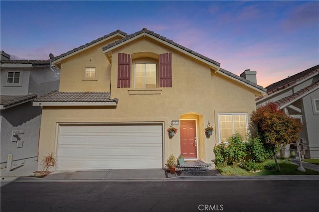 view of front of property with an attached garage, a chimney, stucco siding, and a tile roof