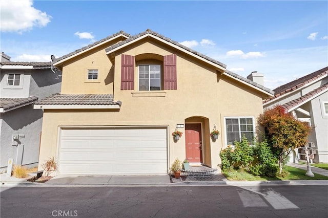 view of front facade featuring an attached garage, stucco siding, and a tiled roof