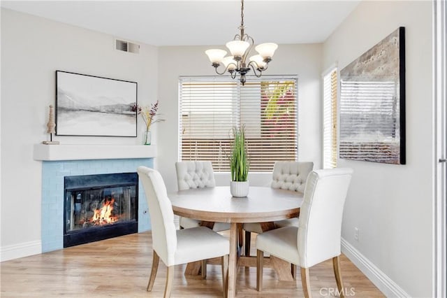 dining room with a chandelier, a healthy amount of sunlight, visible vents, and wood finished floors