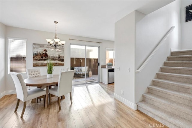 dining room with light wood-type flooring, stairs, baseboards, and a notable chandelier