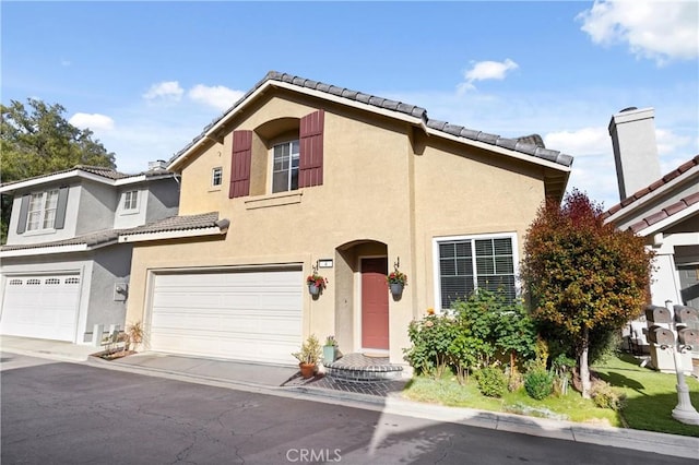 view of front of home with stucco siding, a tile roof, and a garage