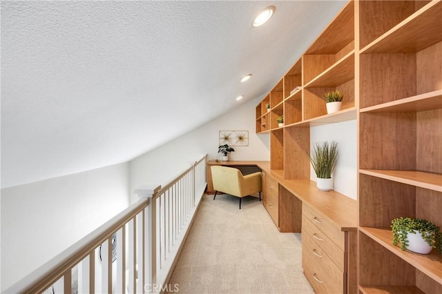 office featuring light colored carpet, built in desk, a textured ceiling, recessed lighting, and vaulted ceiling