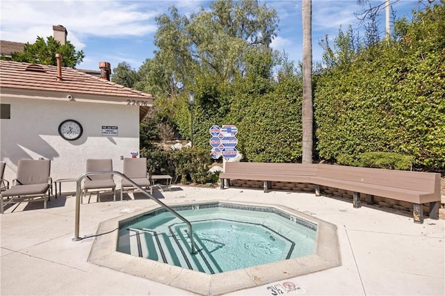 view of pool with a hot tub and a patio