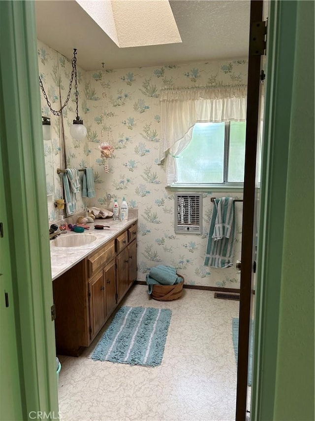 bathroom featuring a skylight, visible vents, wallpapered walls, and vanity
