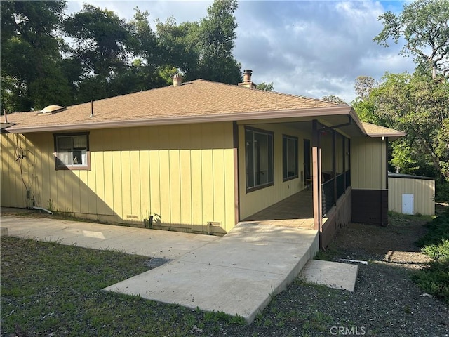 view of property exterior with a patio and roof with shingles