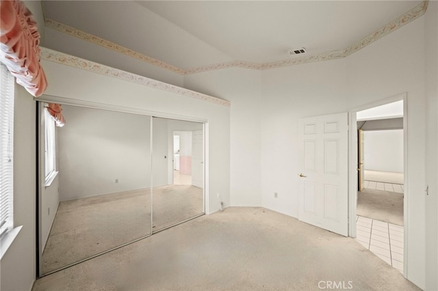 unfurnished bedroom with visible vents, carpet, and a closet