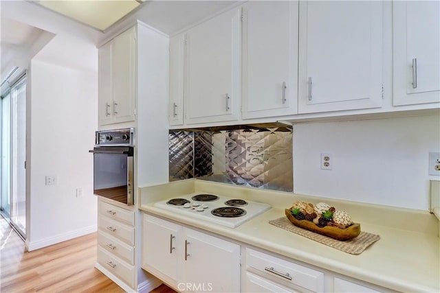 125 Via Estrada Unit B, Laguna Woods, CA 92637 - kitchen featuring tasteful backsplash, white electric stovetop, light countertops, white cabinets, and oven
