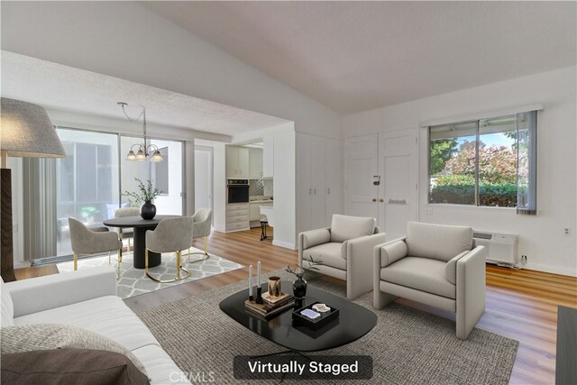 125 Via Estrada Unit B, Laguna Woods, CA 92637 - living room with vaulted ceiling, light wood-style flooring, a wealth of natural light, and a notable chandelier