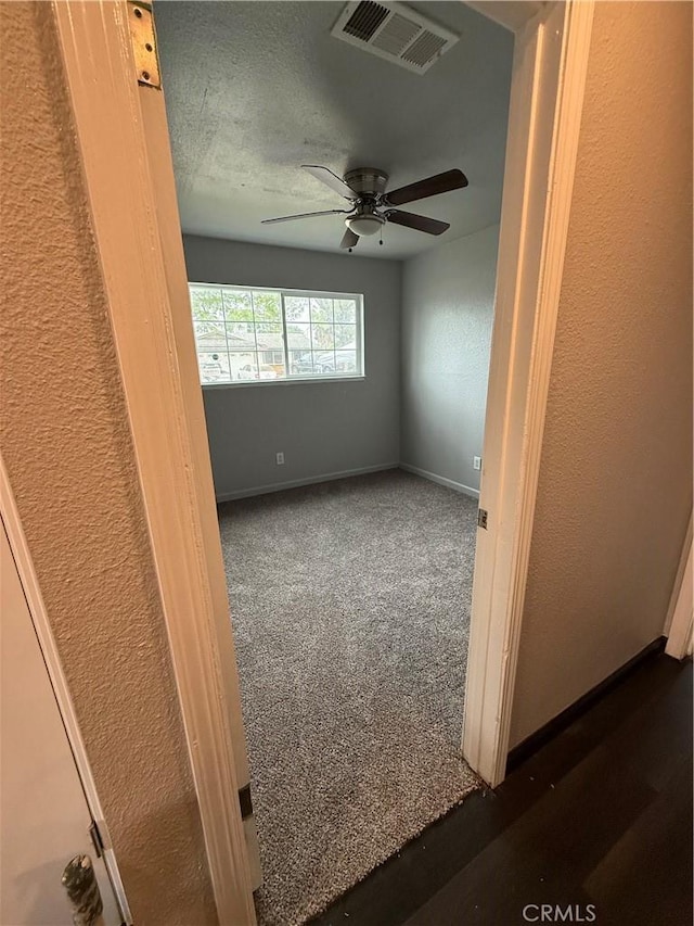 empty room featuring baseboards, ceiling fan, a textured wall, and visible vents