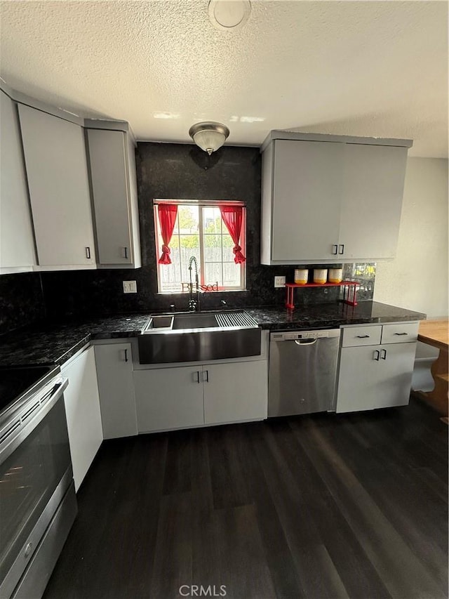 kitchen featuring white cabinets, a sink, dark wood finished floors, stainless steel appliances, and decorative backsplash