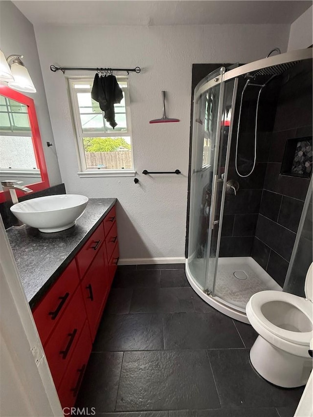bathroom with vanity, baseboards, toilet, and a shower stall