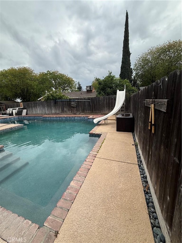view of swimming pool featuring a fenced in pool, a fenced backyard, and a water slide