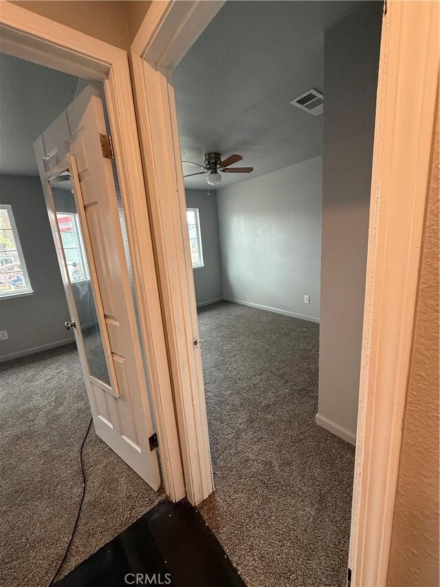 corridor with carpet floors, visible vents, and a healthy amount of sunlight