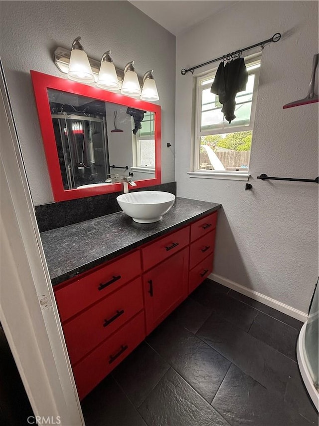 bathroom with vanity, baseboards, a textured wall, and tile patterned flooring