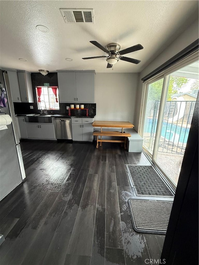 interior space with a sink, a healthy amount of sunlight, a textured ceiling, and visible vents