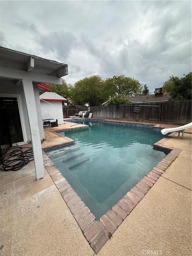 view of pool featuring a fenced in pool, a fenced backyard, a patio area, and a water slide