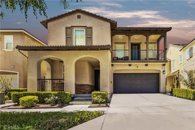 mediterranean / spanish-style house featuring stucco siding, an attached garage, driveway, and a balcony