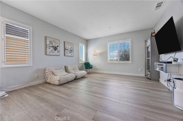 sitting room with baseboards, light wood finished floors, and visible vents
