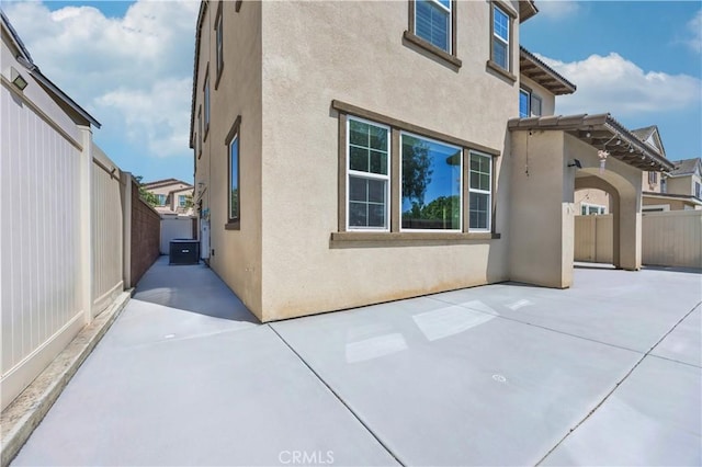 view of side of property with a patio area, stucco siding, and fence
