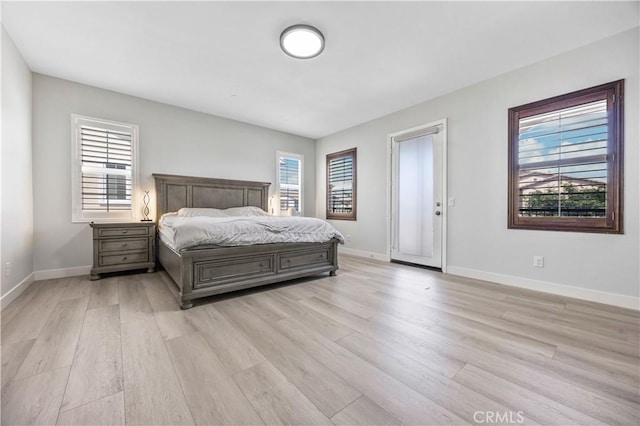 bedroom with light wood-style floors, baseboards, and access to outside