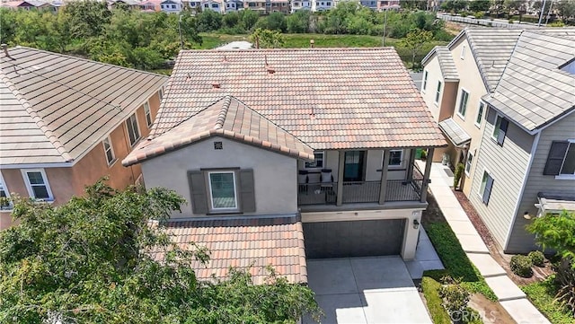 view of front of property featuring driveway, a tile roof, a residential view, an attached garage, and stucco siding