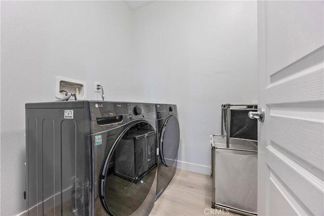laundry room with separate washer and dryer, laundry area, baseboards, and wood finished floors