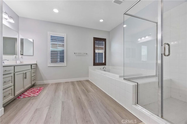 full bathroom with a stall shower, wood finished floors, a garden tub, and vanity