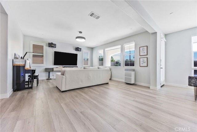 living area featuring visible vents, light wood-style floors, and baseboards