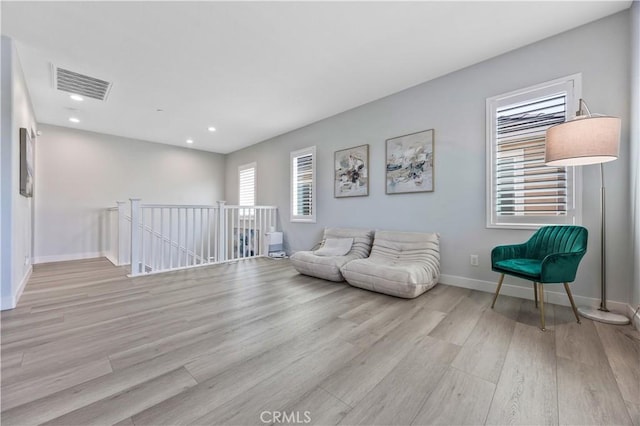 living area featuring visible vents, wood finished floors, baseboards, recessed lighting, and an upstairs landing