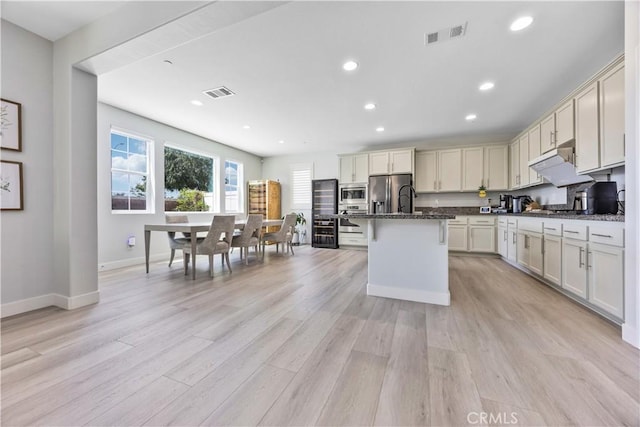 kitchen featuring an island with sink, light wood-style flooring, stainless steel appliances, recessed lighting, and visible vents