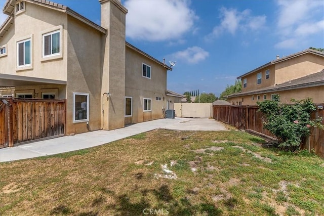 back of house with a lawn, a fenced backyard, a patio area, and stucco siding