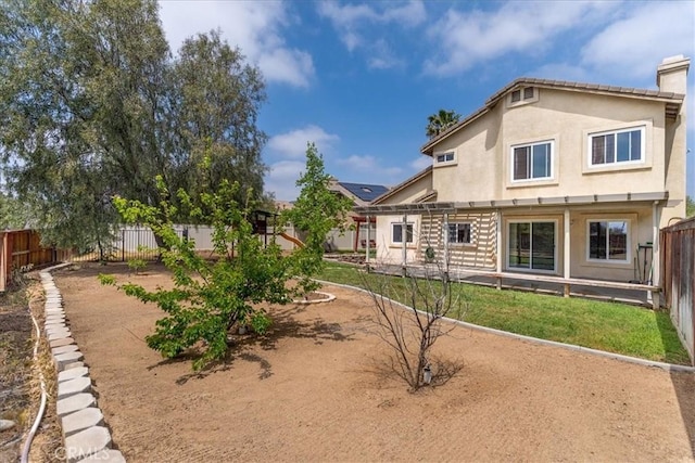 rear view of property featuring a fenced backyard, stucco siding, a pergola, and a chimney