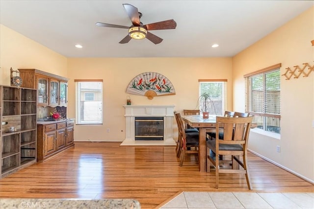 dining space featuring light wood-style floors, recessed lighting, a ceiling fan, and a glass covered fireplace