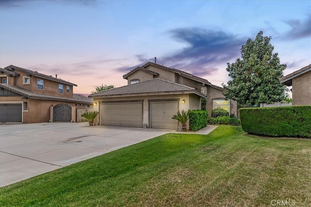 view of front of house featuring a lawn, an attached garage, stucco siding, and concrete driveway