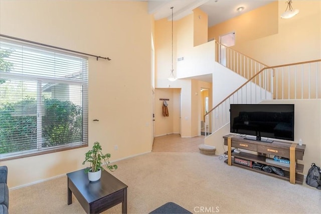 living area featuring visible vents, carpet flooring, a high ceiling, and stairway