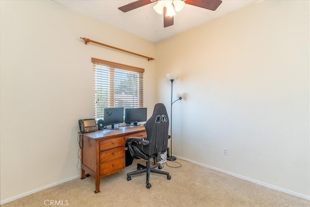 office space featuring baseboards, a ceiling fan, and light colored carpet