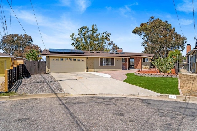 single story home with an attached garage, a gate, roof mounted solar panels, and driveway
