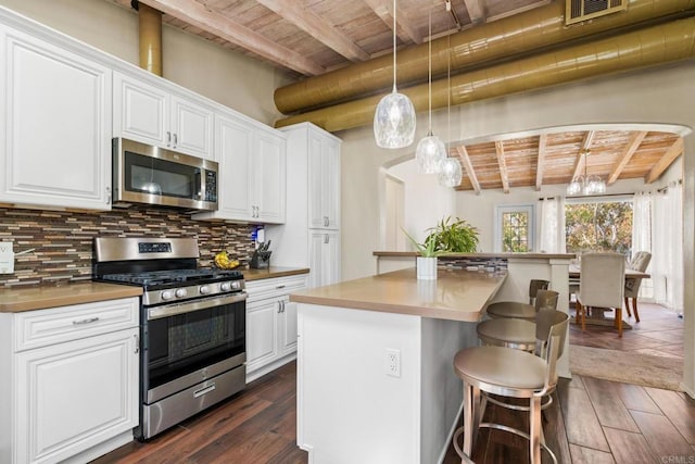 kitchen with beam ceiling, stainless steel appliances, wooden ceiling, tasteful backsplash, and visible vents