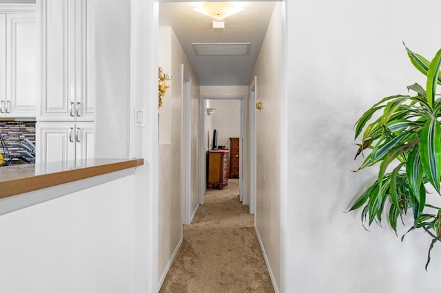 corridor featuring visible vents, baseboards, and light carpet
