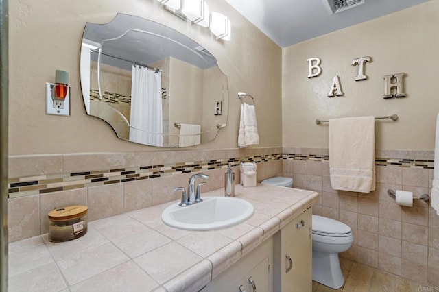 full bathroom with wainscoting, tile walls, vanity, and toilet