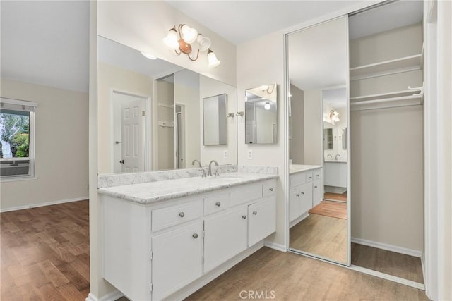 bathroom featuring vanity, baseboards, wood finished floors, and cooling unit