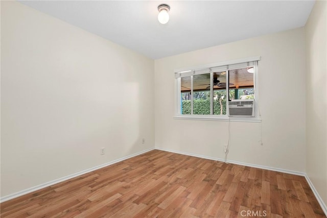 spare room with baseboards and light wood-type flooring