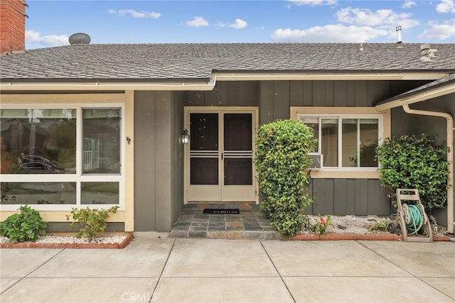 doorway to property featuring roof with shingles